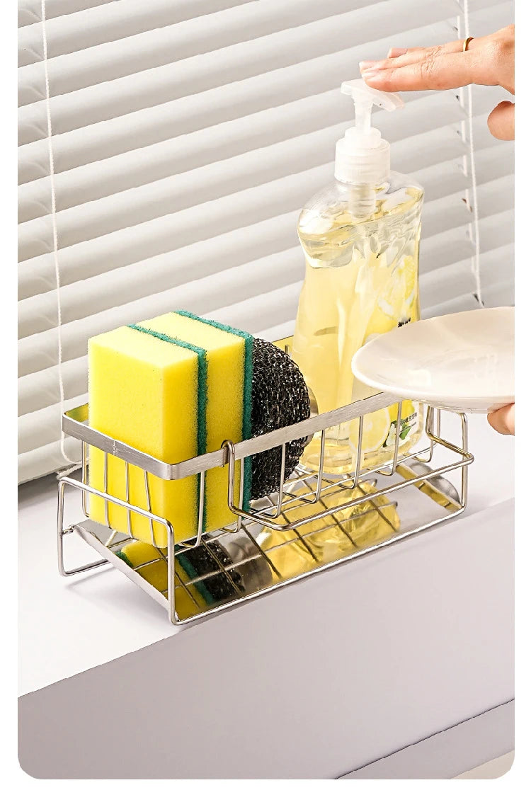 Cleaning supplies including a bottle, sponge, and scrubber in a metal caddy with a window blind background.