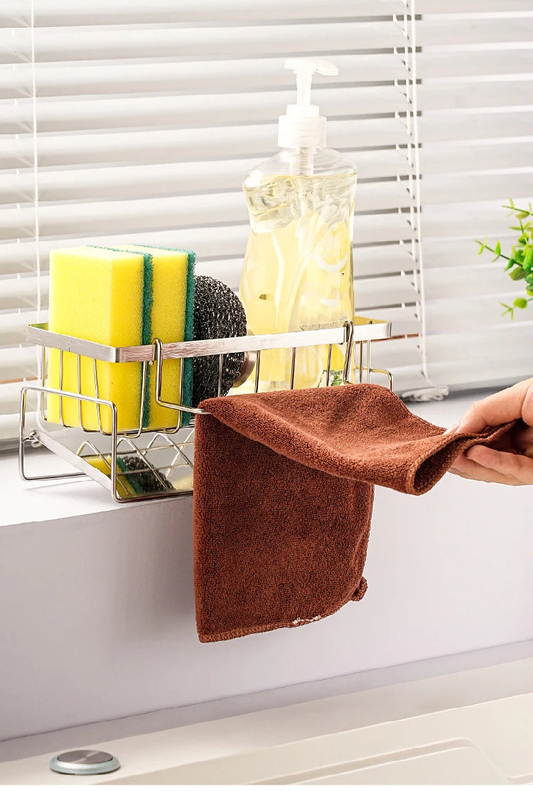 Cleaning supplies including a brown towel, sponges, and a bottle on a window sill with blinds.