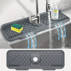 Gray silicone sink mat with water drainage holes in a kitchen setting.