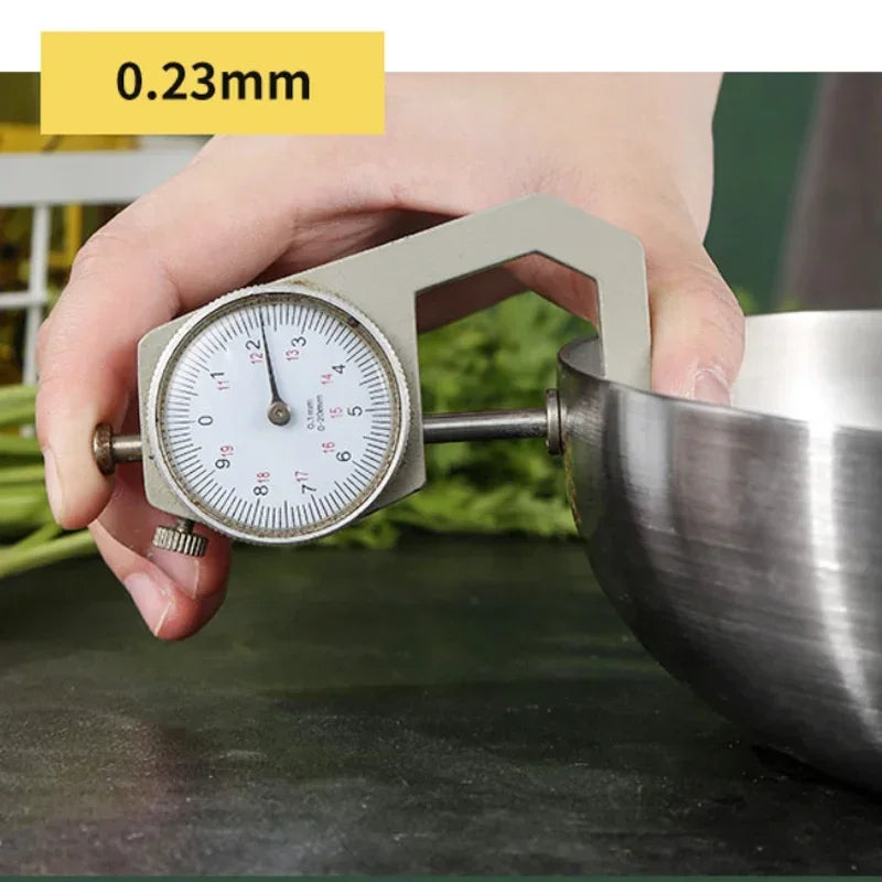 Hand holding a dial indicator against a metal bowl with a blurred background