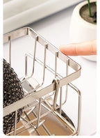 Metal kitchen rack with sponge and scrubber on a white surface
