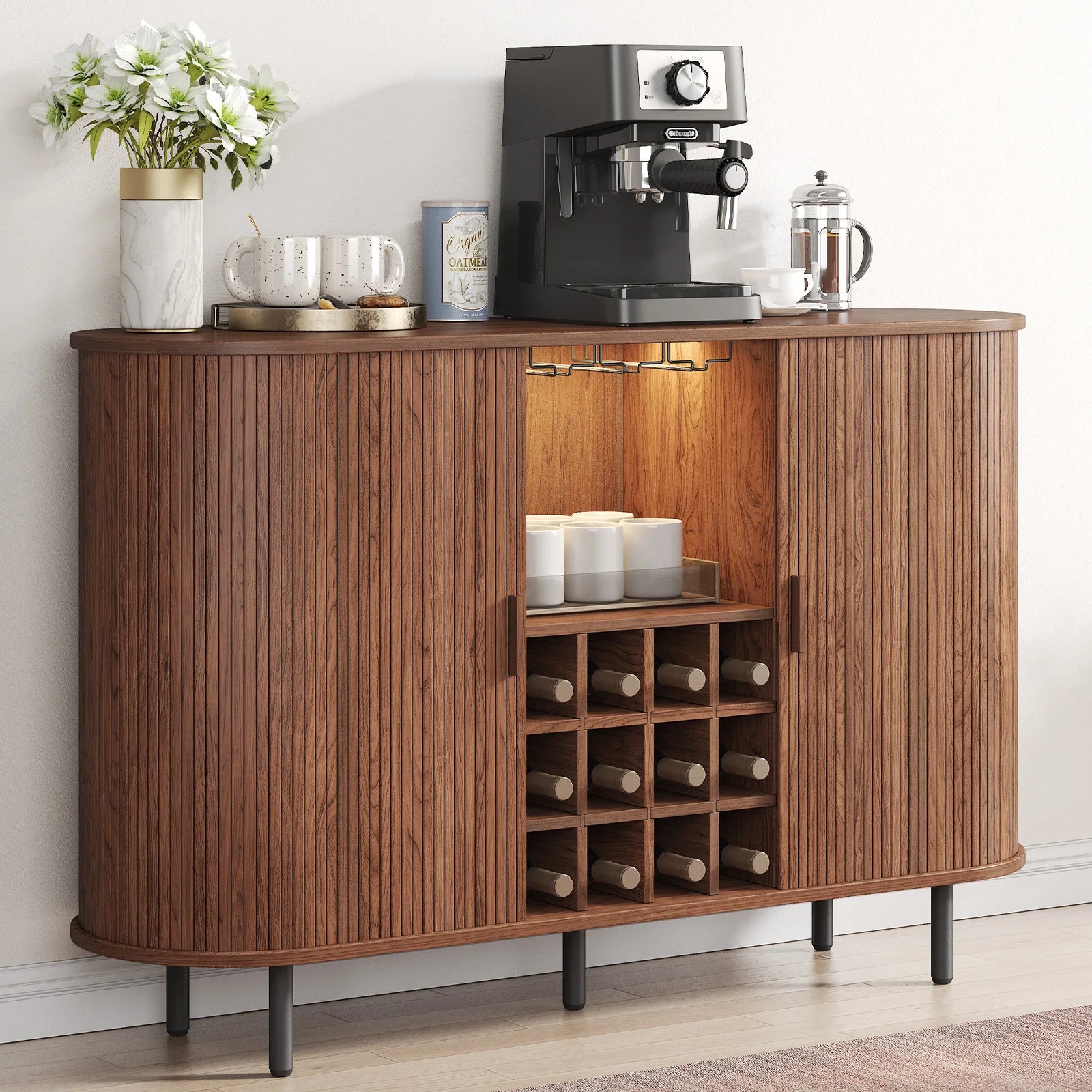 Wooden bar cabinet with open door displaying bottles, coffee maker, and other items on a white wall background.