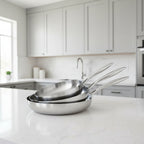 Set of three stainless steel frying pans with handles on a white background
