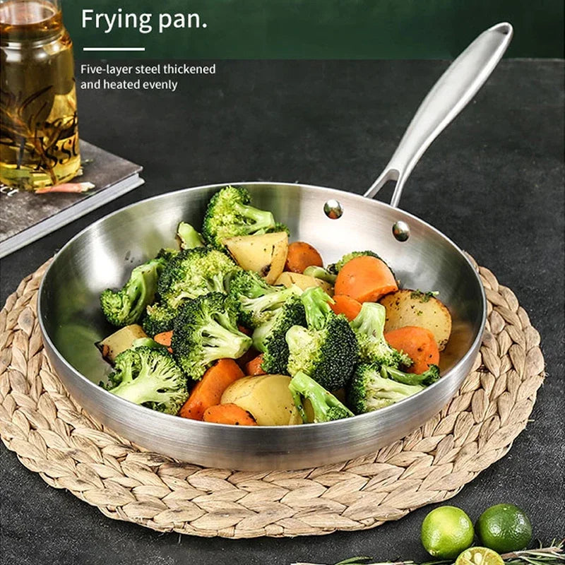 Stainless steel frying pan with vegetables on a woven mat